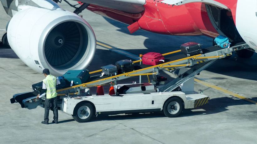 Un trabajador descargando las maletas de un avión