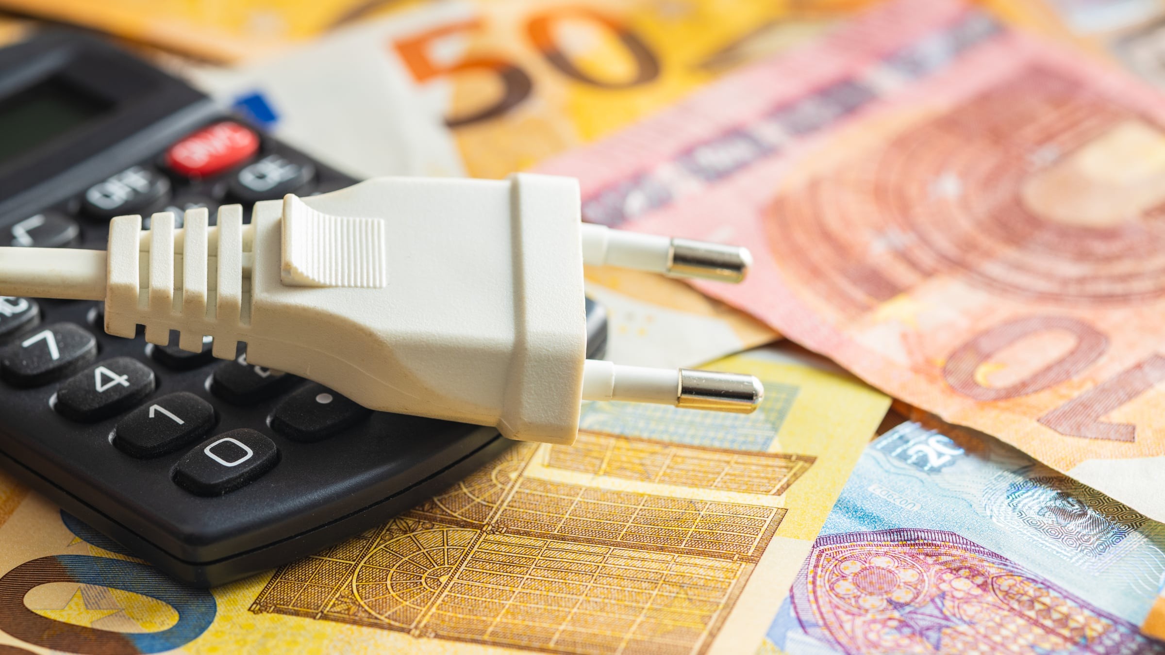 Facturas de luz junto a una calculadora y dinero en efectivo