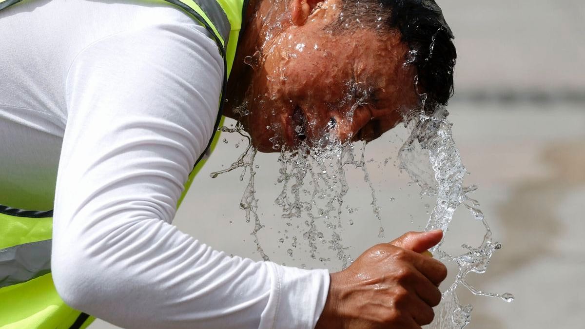 Hombre echándose agua con la manguera