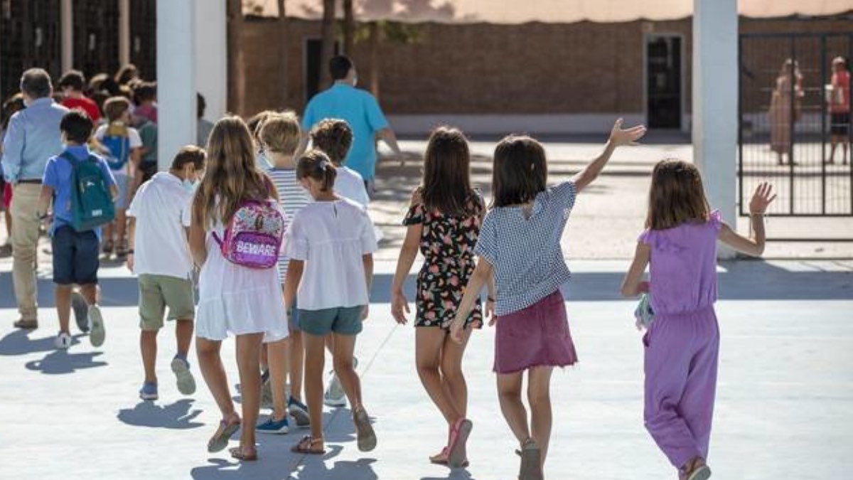 Niños y niñas echados caminando por el patio del colegio