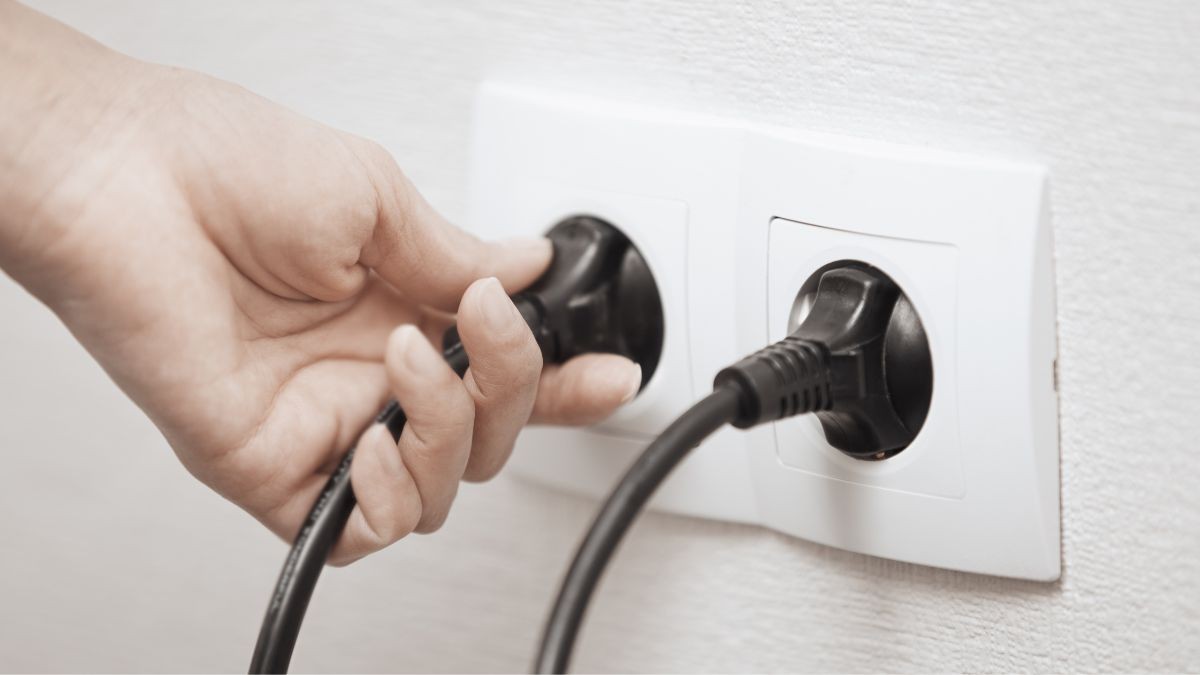 Una mujer sujeta un cable enchufado con la mano.