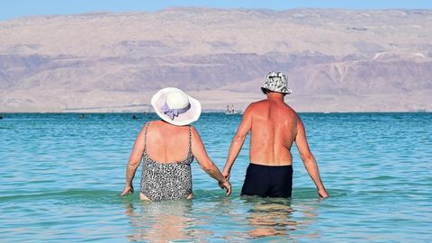 Dos mayores de la mano entran en el mar.