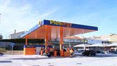 Dos trabajadores frente a una estación de servicio Plenergy.