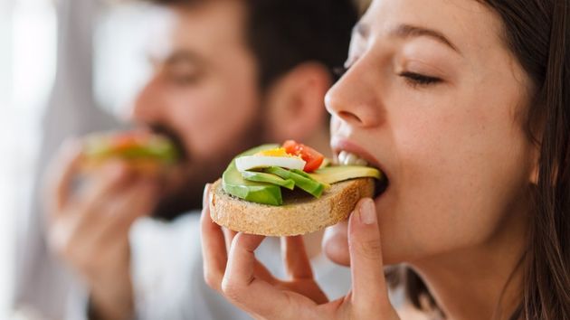 Una mujer comiendo una tostada con aguacate