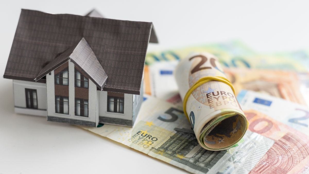 Billetes de euro junto a una figura de una casa