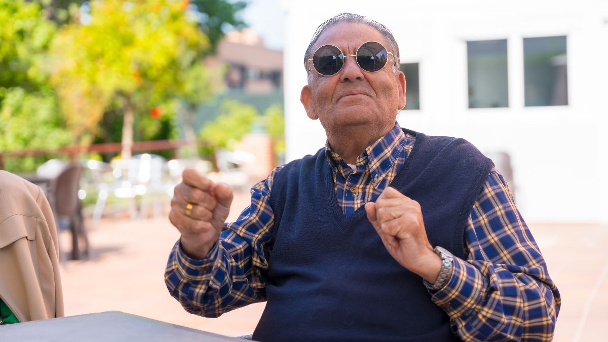 Un jubilado sonriente sentado en un patio Un jubilado sonriente sentado en un patio