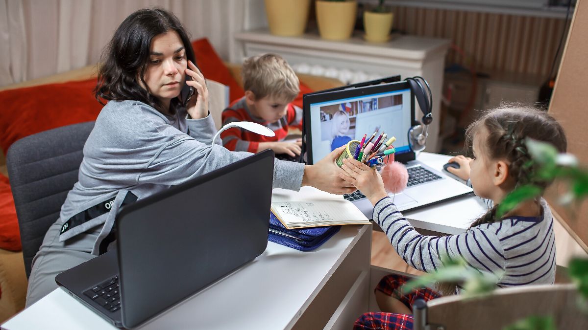 Una mujer teletrabajando en casa, con sus hijos Una mujer teletrabajando en casa, con sus hijos