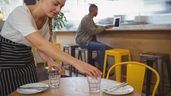 Una camarera recogiendo la mesa