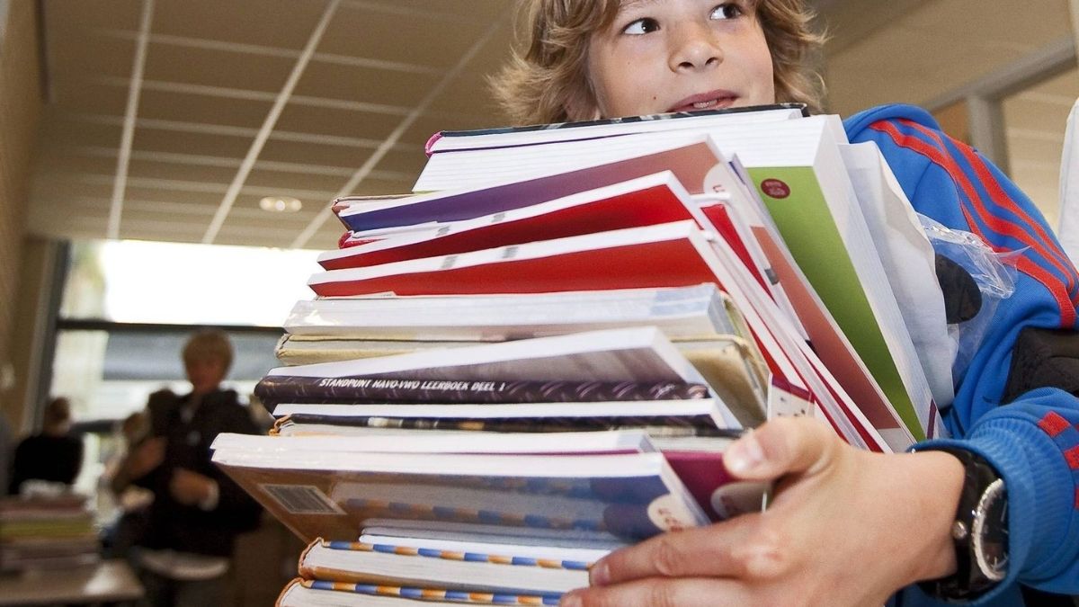 Un niño cargando con libros en un colegio. Niño con tablet