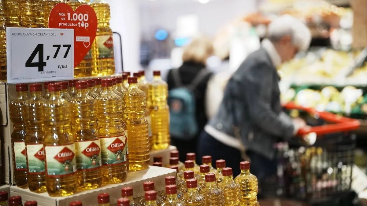 Mujer comprando en un supermercado con varias botellas de aceite de oliva al lado. Aceite de oliva