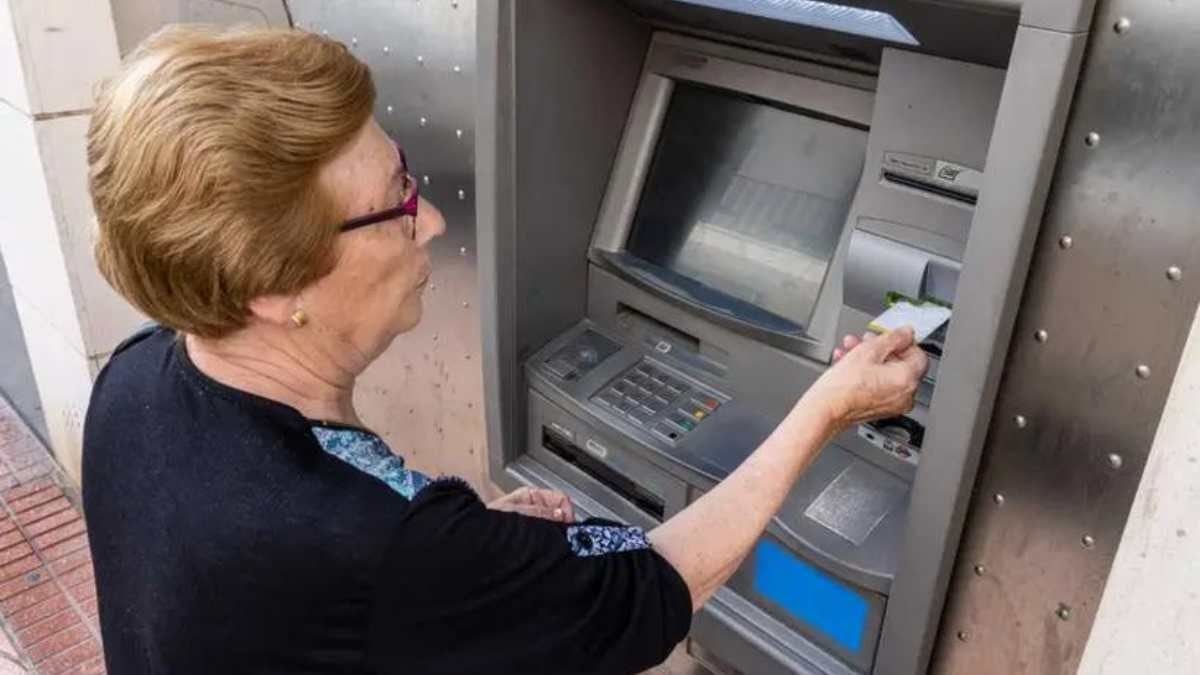 Pensionista sacando el dinero de su pensión de un cajero automático