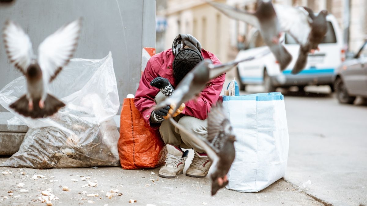 Una persona sin hogar en la calle. Vagabundo con palomas