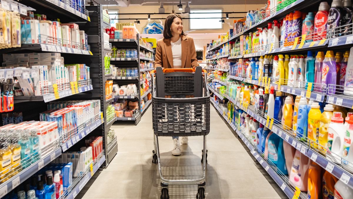 Una chica comprando por un pasillo de un supermercado español Una chica con un carro de supermercado por un pasillo