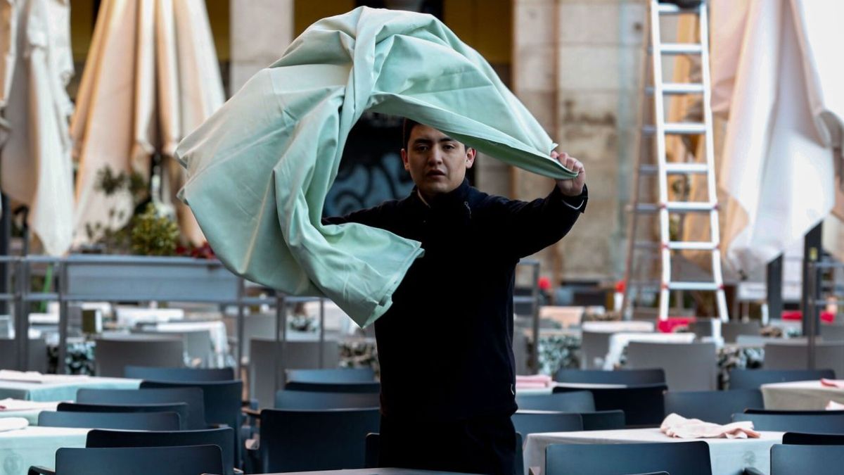Un camarero pone el mantel en una mesa de restaurante. camarero trabajando