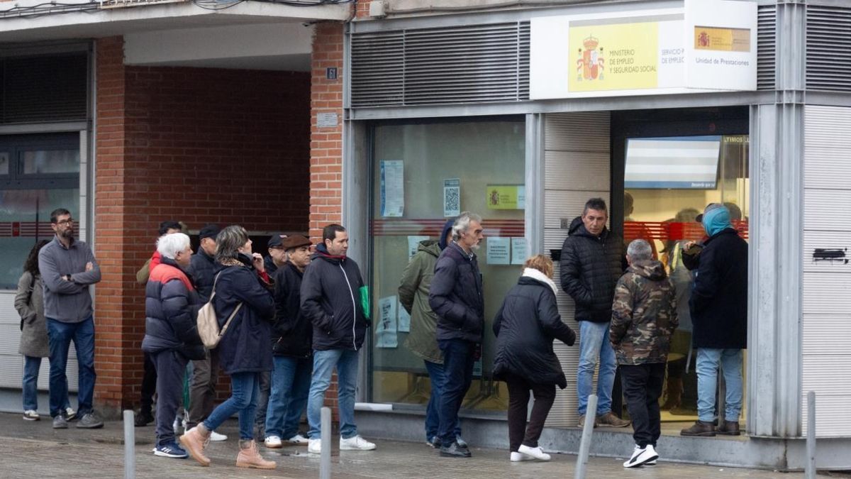 Varias personas en fila esperando para entrar en una oficina de empleo. Fila de parados