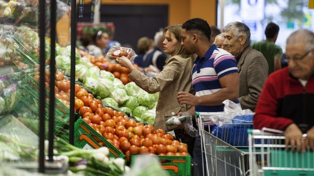 Varias personas compran fruta en un supermercado. Comprando fruta en supermercado