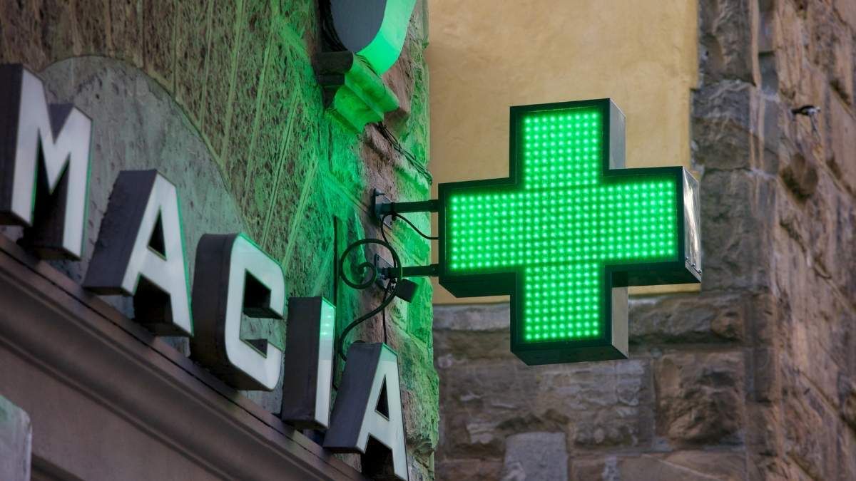 Un letrero de farmacia Letrero de farmacia con la cruz verde encendida