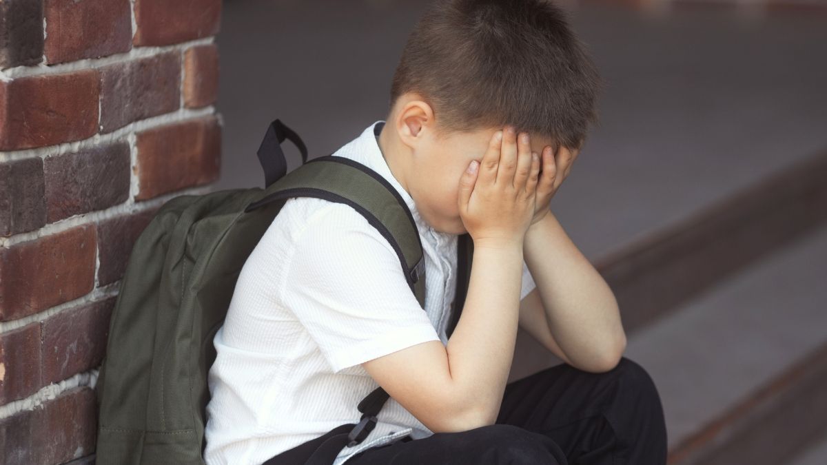 Un niño llora con las manos en la cara. Niño triste