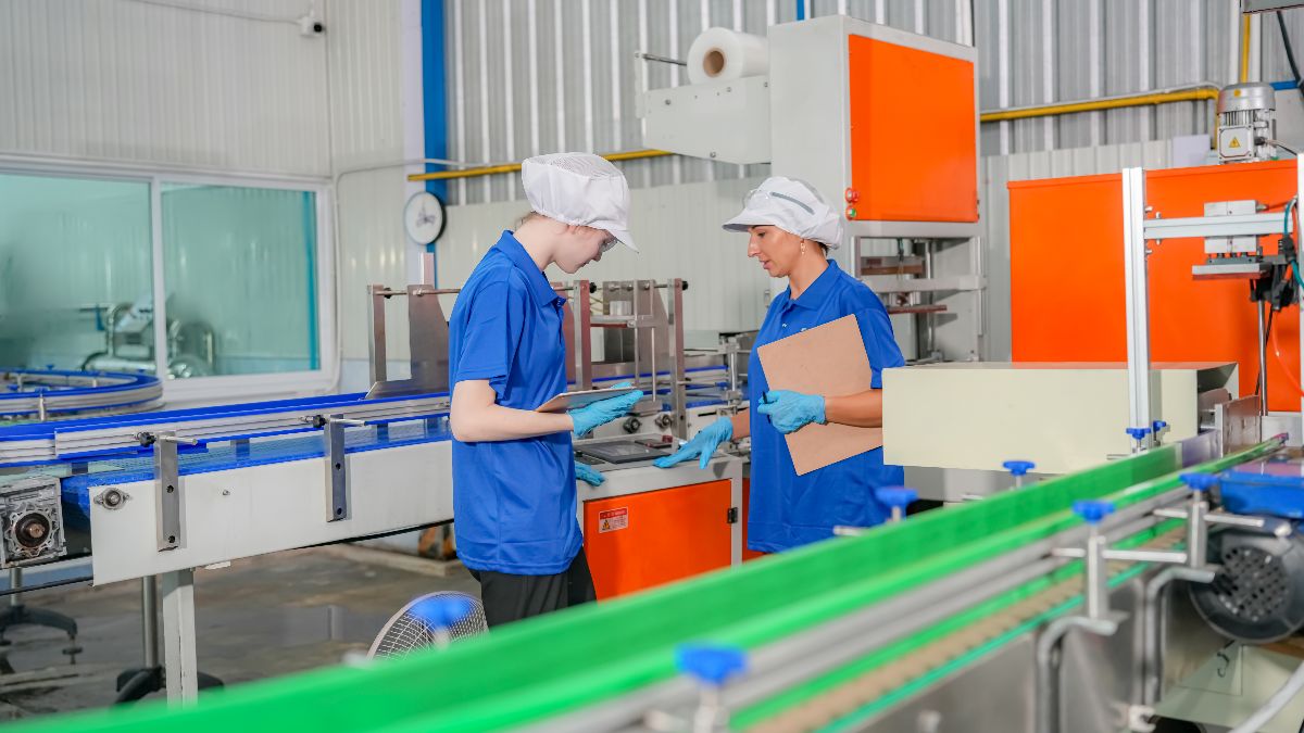 Operarias de producción trabajando en una empresa de envasado Dos operarias de producción en una empresa de envasado alimentario