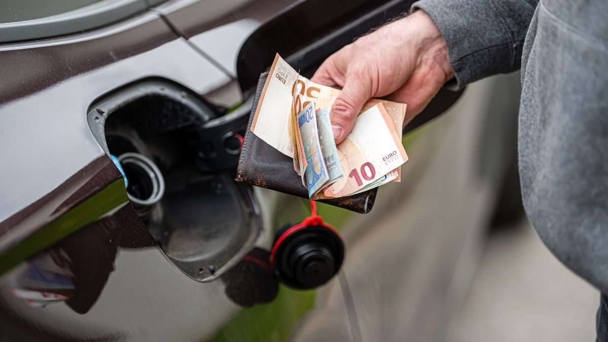 Un hombre sujetando billetes de euro con el depósito de gasolina abierto Un hombre sujetando billetes de euro con el depósito de gasolina abierto