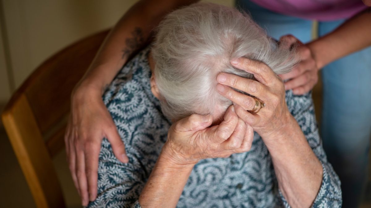 Una mujer llorando recibe el apoyo de una persona más joven. Mujer mayor triste
