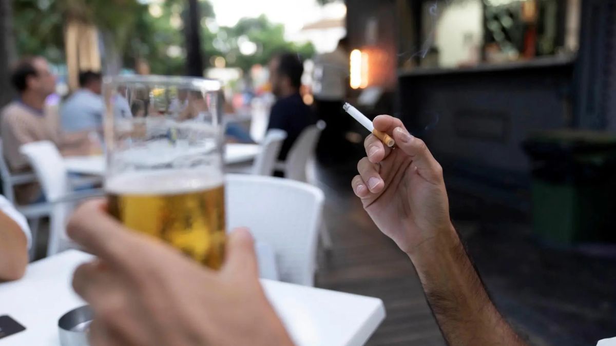 Persona fumando en la terraza de un bar Persona fumando en la terraza de un bar