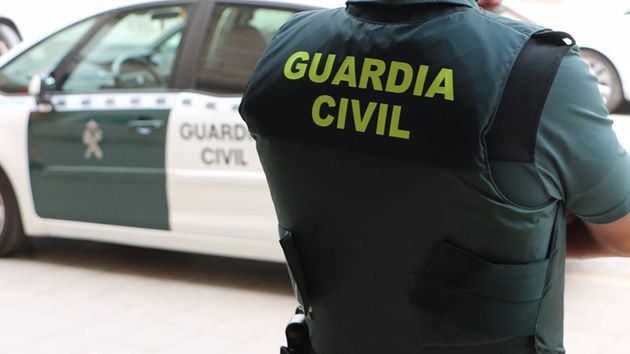 Un agente de la Guardia Civil, de espaldas, junto a un vehículo oficial