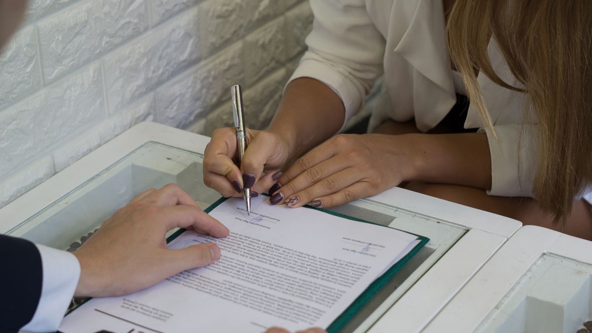 Dos personas firmando un contrato de trabajo Dos personas firmando un contrato de trabajo