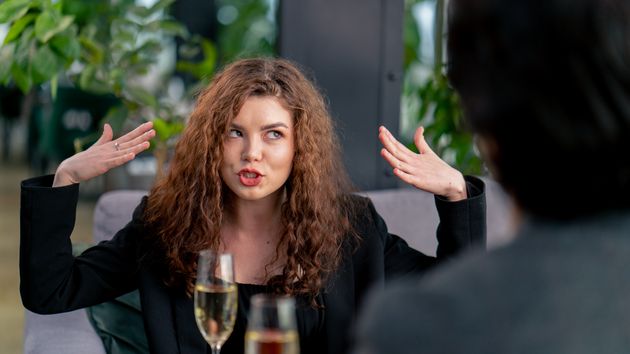 Una mujer gesticula sentada en una mesa