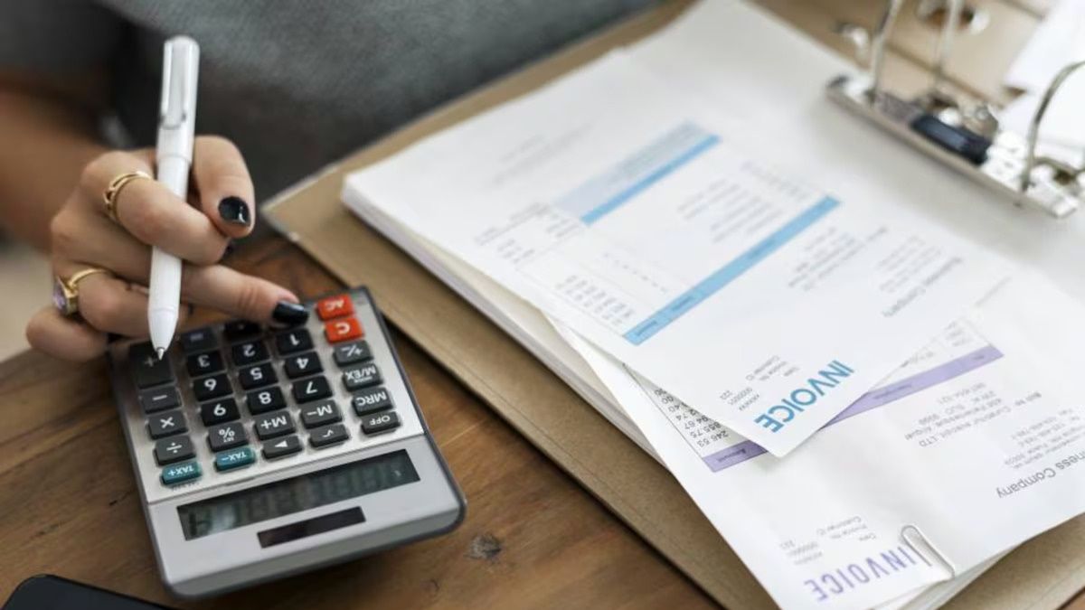Estos errores como autónomo te pueden salir muy caros cuando emitas facturas Una persona utilizando una calculadora junto a documentos y facturas