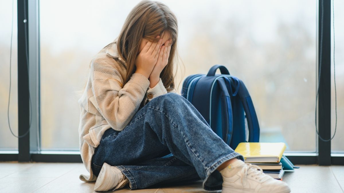 Una niña con altas capacidades se niega a ir al colegio por lo que dijo la maestra a su padre Una niña llorando con su mochila al lado