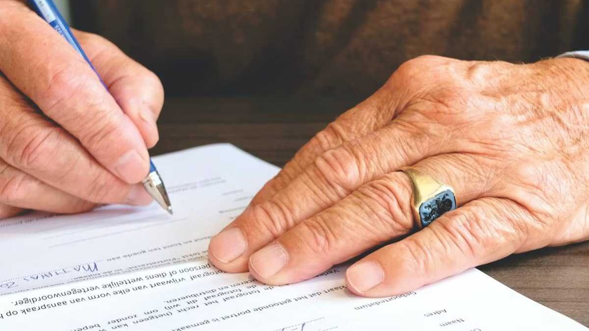 Las manos de un anciano firmando un testamento Las manos de un anciano firmando un testamento