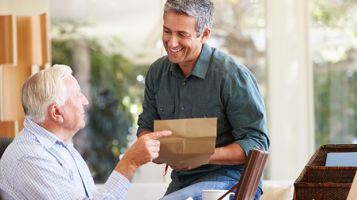 Un anciano dándole un documento a su hijo