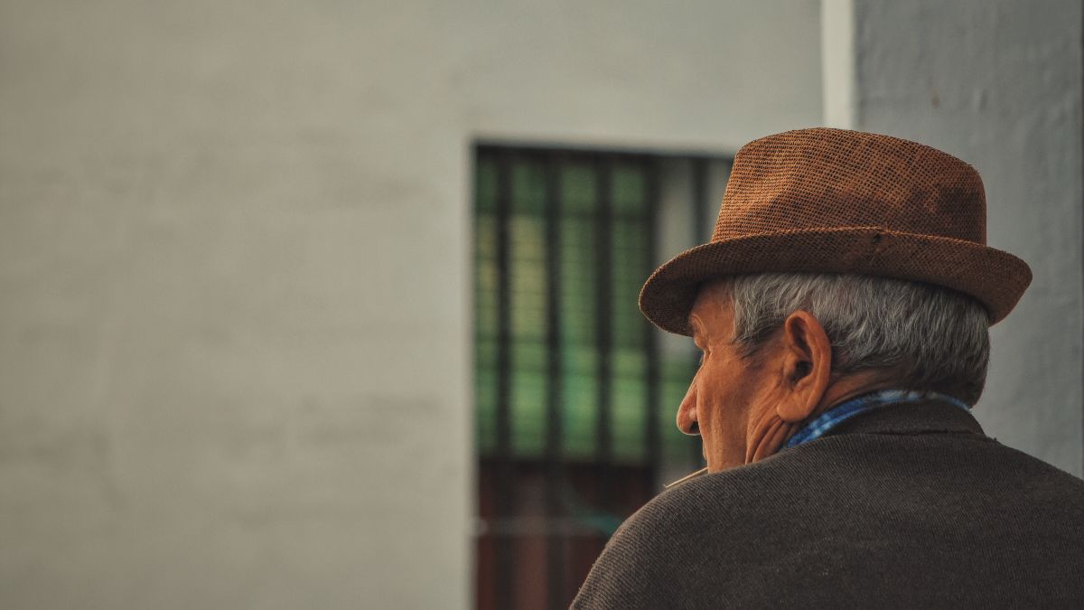 Un anciano frente a una casa 