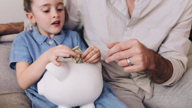Hija con su padre sacando dinero de la hucha