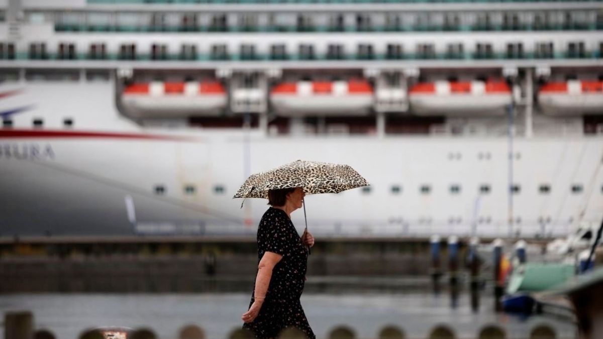 Una mujer con un paraguas pasa delante de un crucero