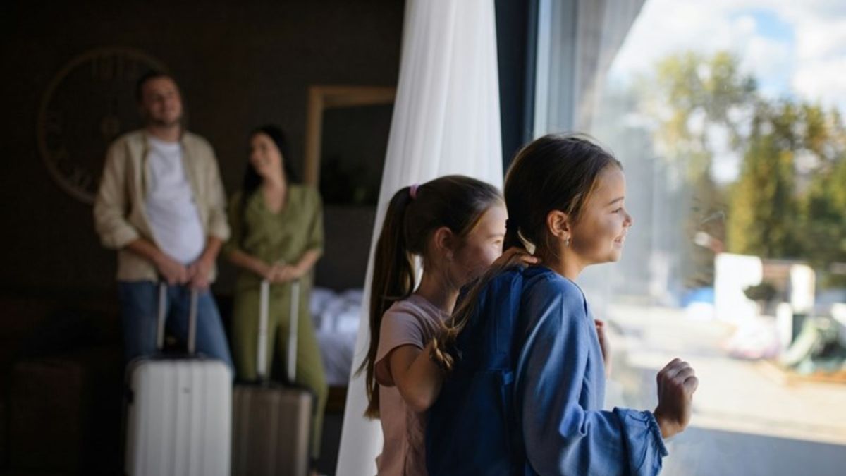 Una familia con unos niños mirando por la ventana