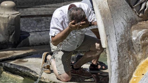 Un hombre mayor refrescándose en una fuente