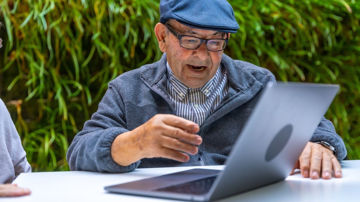 Un anciano con un ordenador en la mesa