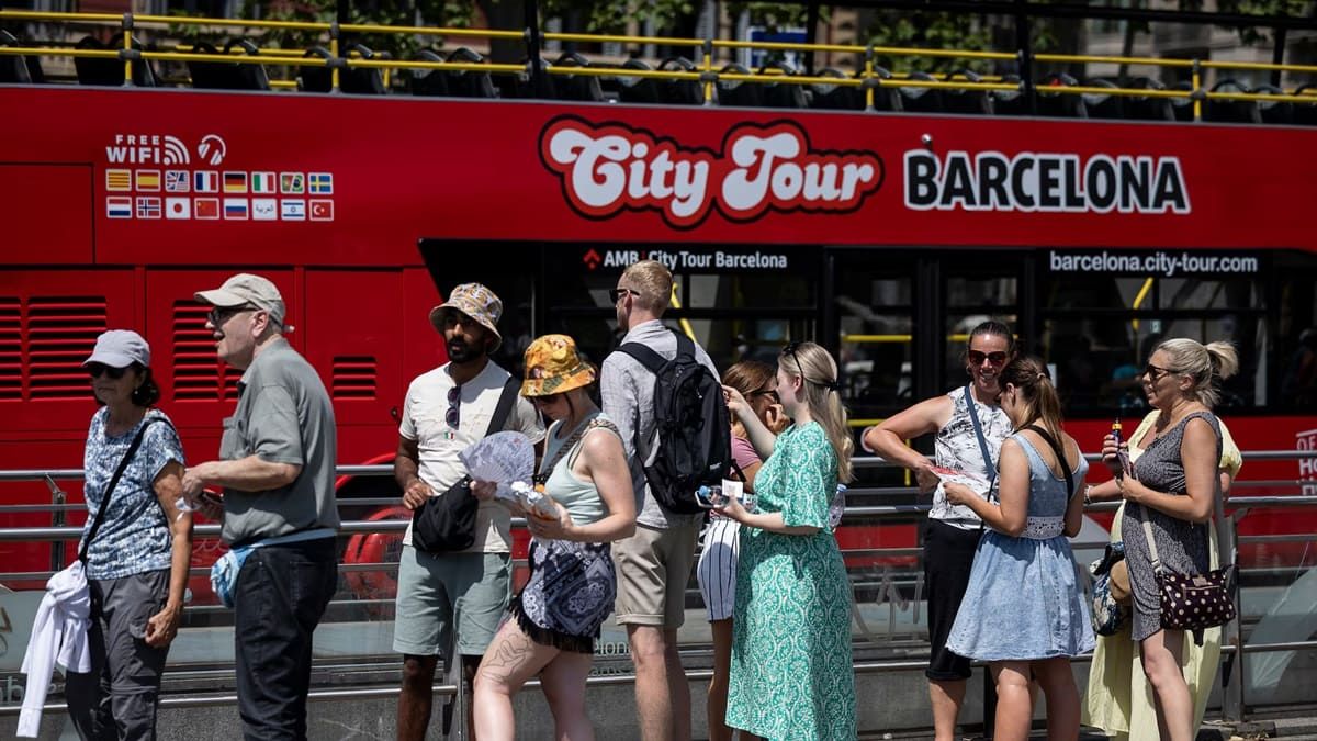 Turistas haciendo cola para subir a un autobús turístico en Barcelona