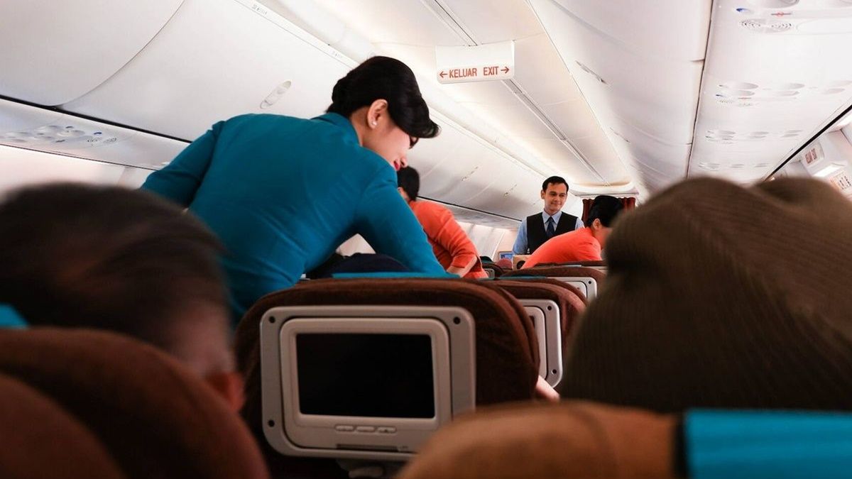 Una azafata de vuelo atiende a pasajeros a bordo de un avión