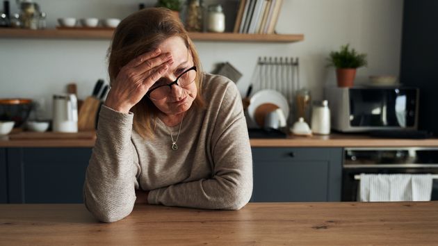 Mujer triste en la cocina de su casa