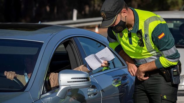 Un agente de la Guardia Civil de Tráfico comprueba un documento aportado por un conductor