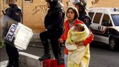 Una mujer con un bebé siendo desalojada por la policía