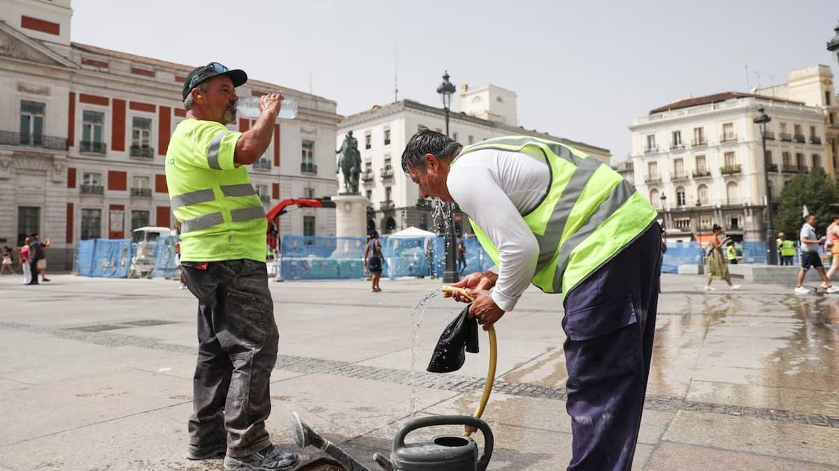 Dos trabajadores se refrescan en Puerta del Sol de Madrid