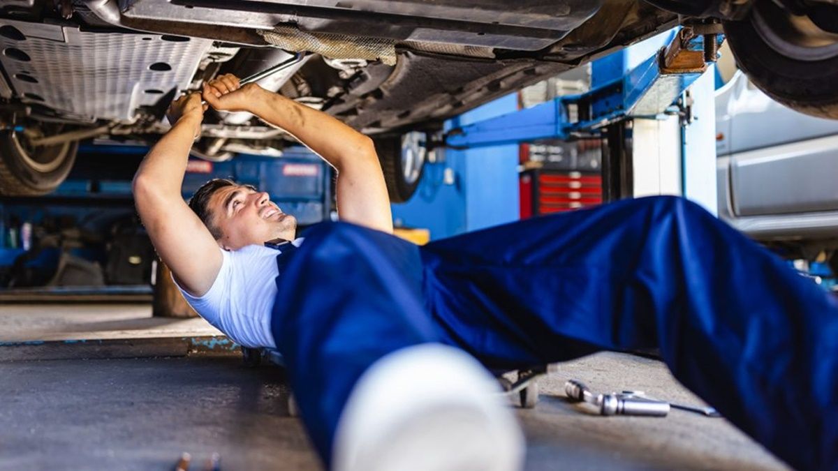 Un mecánico realiza una reparación a un coche en un taller