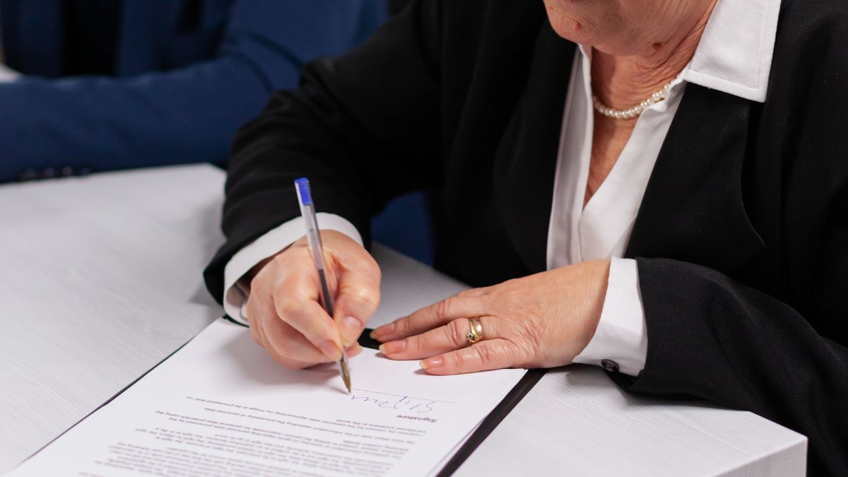 Una anciana firmando un documento 