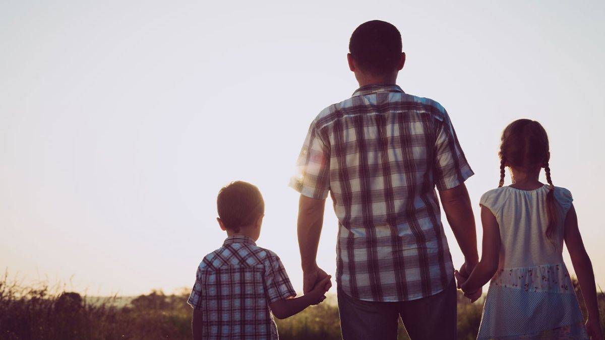 Un padre con dos niños de la mano