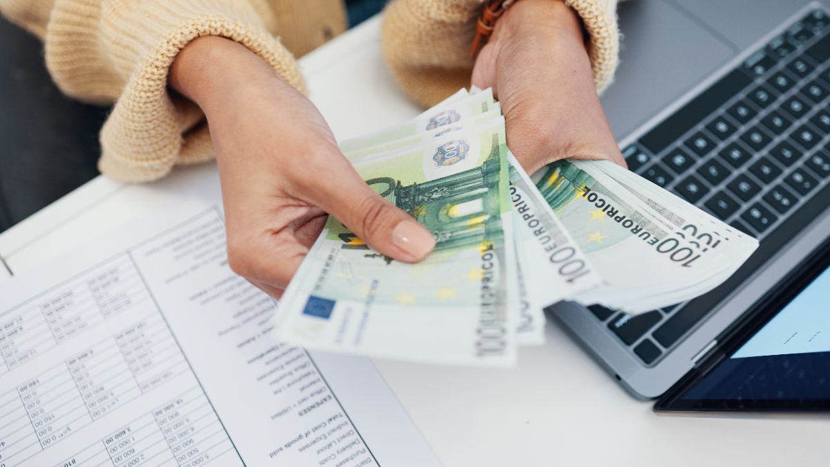 Una mujer con billetes de 100 euros calculando impuestos