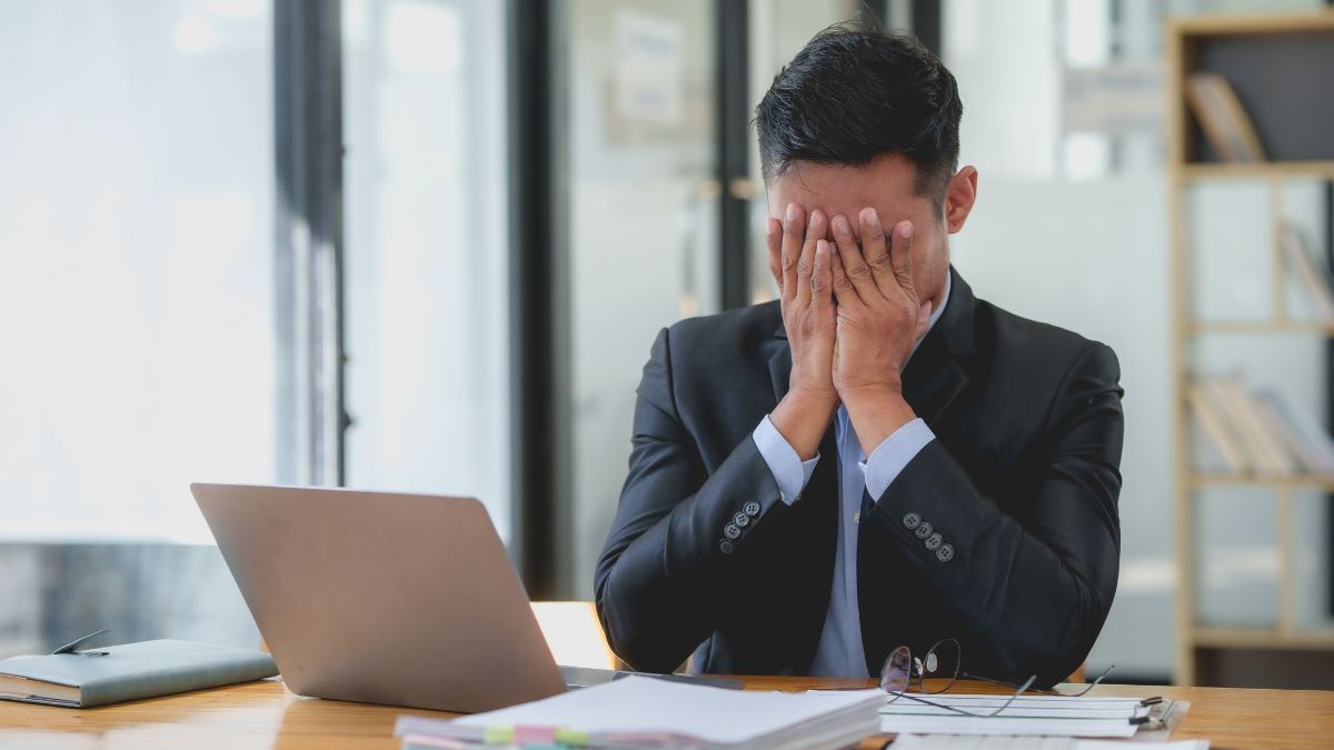 Un trabajador triste en la mesa con las manos en la cara